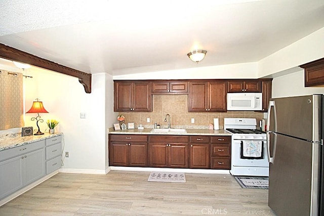 kitchen with white appliances, light stone counters, decorative backsplash, and a sink