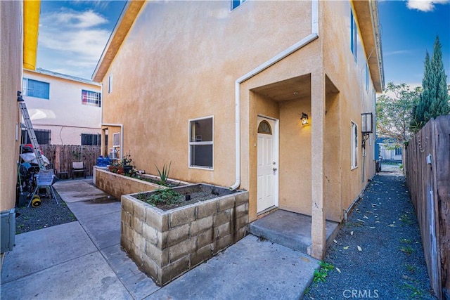 property entrance with a patio area, fence, and stucco siding