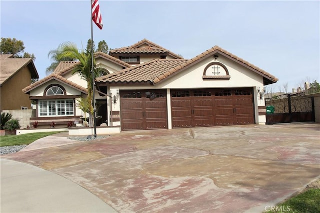 mediterranean / spanish home with concrete driveway, an attached garage, a tile roof, and stucco siding