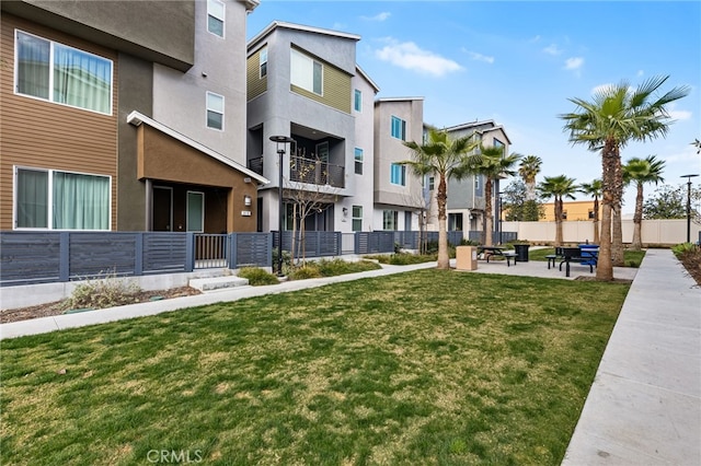 view of community featuring fence and a lawn