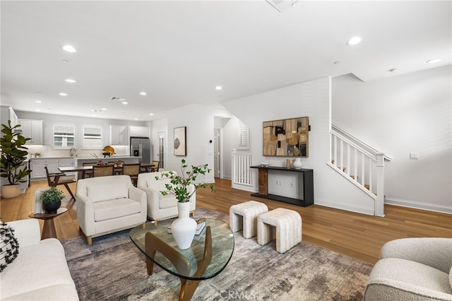 living area with recessed lighting, stairway, baseboards, and wood finished floors