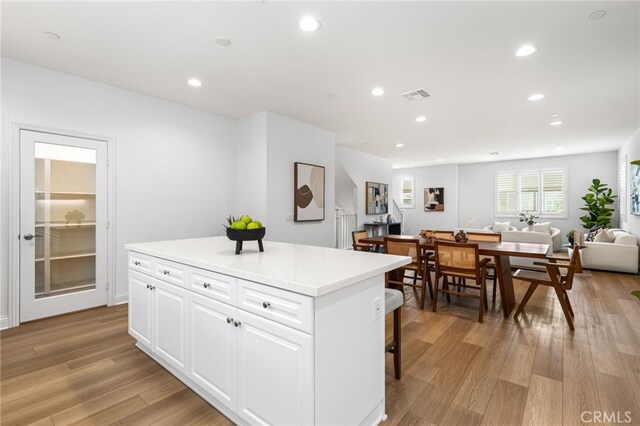 kitchen with a center island, open floor plan, white cabinets, and visible vents