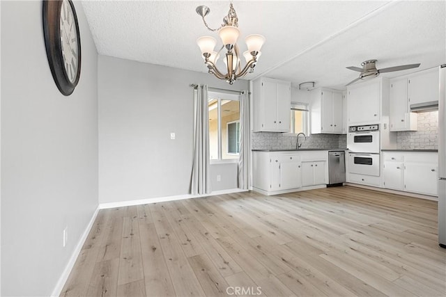 3695 Linden Ave Unit 11A, Long Beach, CA 90807 - kitchen with dark countertops, tasteful backsplash, dishwasher, white double oven, and white cabinetry