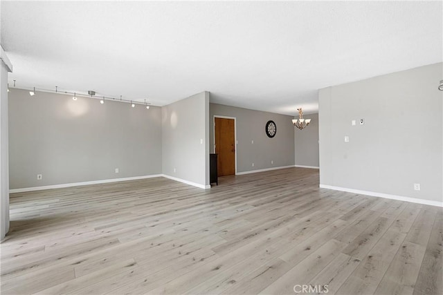 3695 Linden Ave Unit 11A, Long Beach, CA 90807 - unfurnished living room featuring track lighting, an inviting chandelier, light wood finished floors, and baseboards