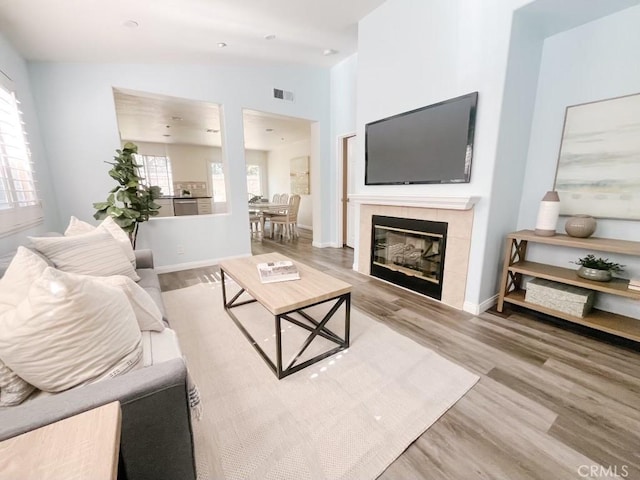 living room featuring a fireplace, wood finished floors, visible vents, and baseboards