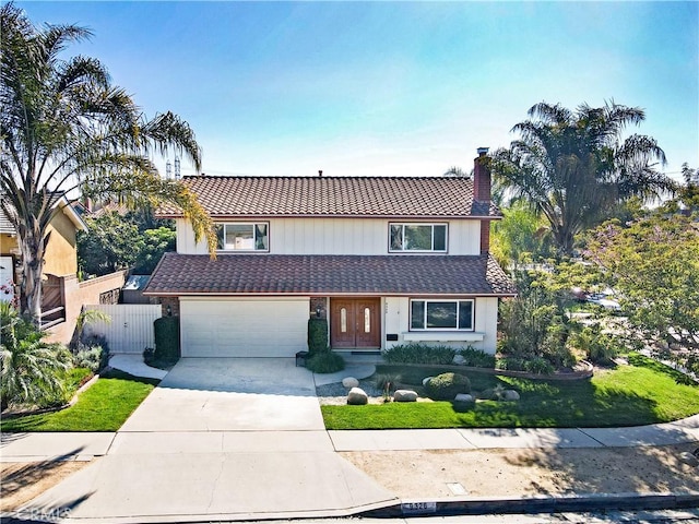 traditional-style home featuring driveway, a tile roof, a chimney, and fence