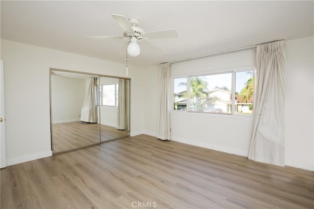 unfurnished bedroom with light wood finished floors, a ceiling fan, baseboards, and a closet