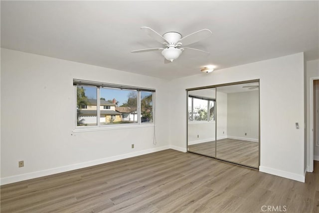 unfurnished bedroom with ceiling fan, a closet, baseboards, and wood finished floors