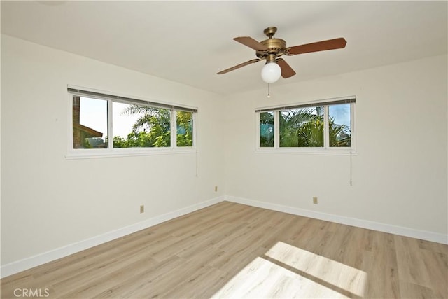 empty room with light wood finished floors, baseboards, and a ceiling fan