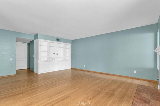 unfurnished living room with light wood-type flooring, baseboards, a fireplace, and visible vents