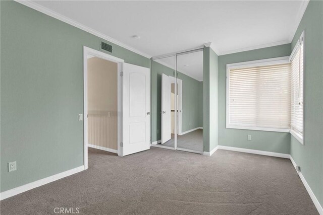 unfurnished bedroom featuring visible vents, baseboards, a closet, carpet, and crown molding