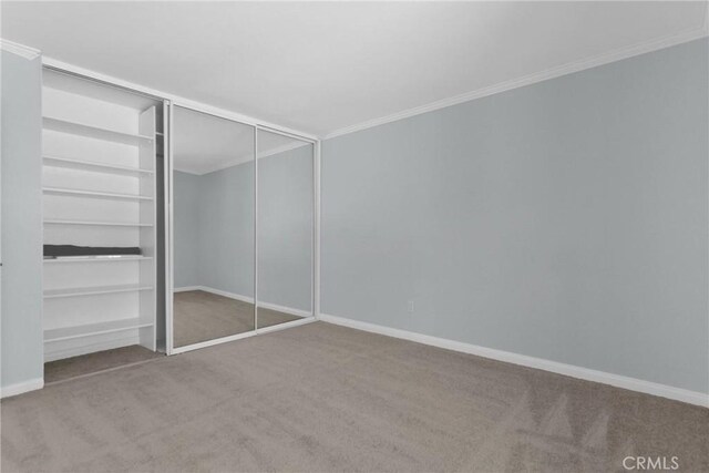 unfurnished bedroom featuring ornamental molding, a closet, carpet, and baseboards