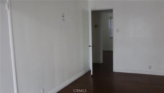 hall featuring dark wood-style flooring and baseboards