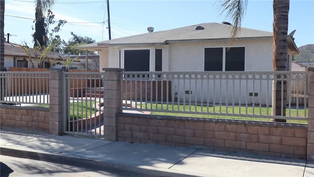 view of front of house featuring a fenced front yard, a shingled roof, a gate, stucco siding, and a front yard