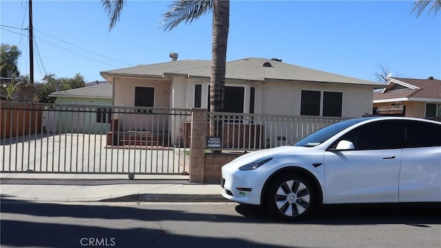 bungalow-style home with a gate, fence, and stucco siding