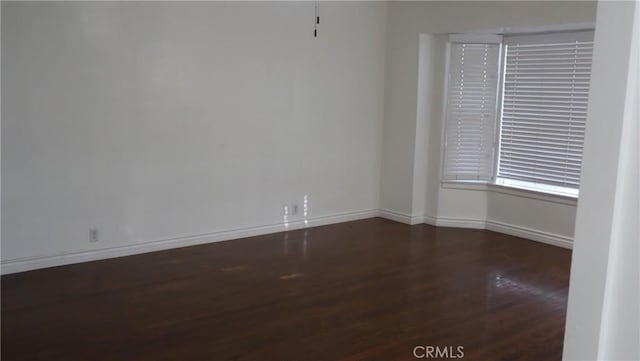 unfurnished room featuring dark wood finished floors and baseboards