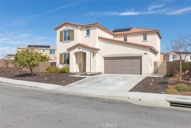 mediterranean / spanish house with a garage, roof mounted solar panels, a tile roof, and driveway