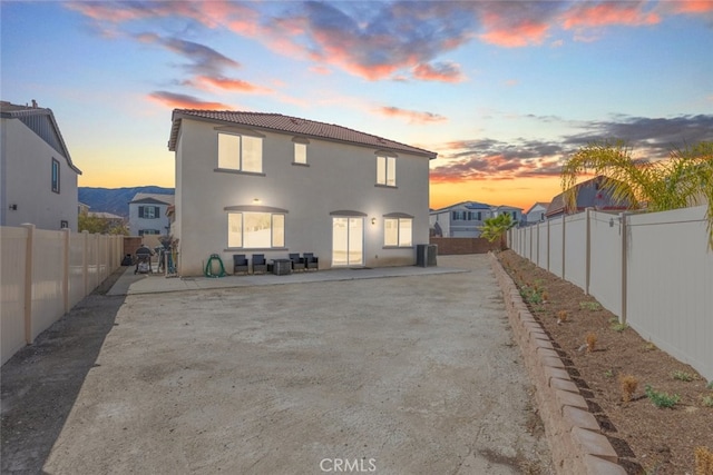 rear view of property featuring stucco siding, a fenced backyard, and a patio