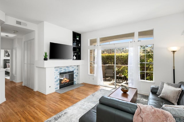 living room featuring visible vents, a fireplace, baseboards, and wood finished floors