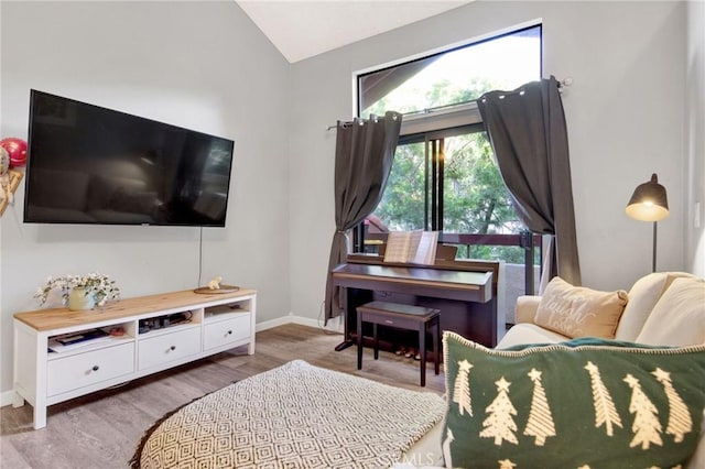 living room with light wood finished floors, baseboards, and vaulted ceiling