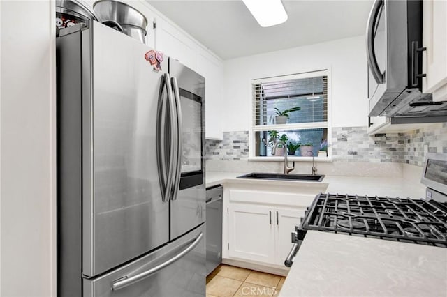 kitchen with stainless steel appliances, light countertops, white cabinets, and a sink