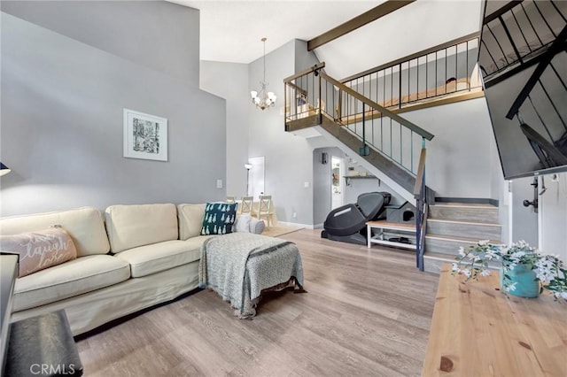 living area featuring baseboards, a chandelier, wood finished floors, stairs, and high vaulted ceiling