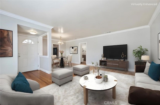 living room with baseboards, wood finished floors, visible vents, and ornamental molding