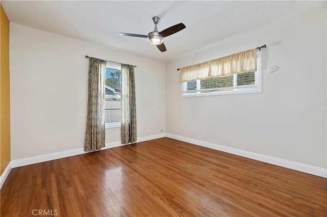 spare room with baseboards, wood finished floors, and a ceiling fan