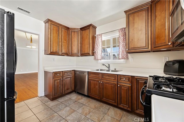 kitchen with visible vents, light countertops, brown cabinets, black appliances, and a sink