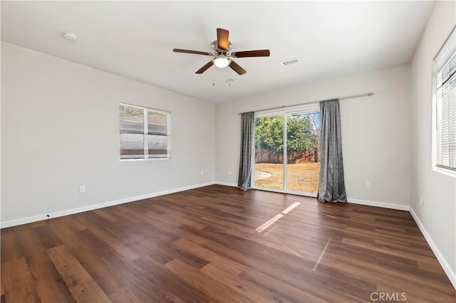 spare room featuring wood finished floors, a healthy amount of sunlight, visible vents, and baseboards