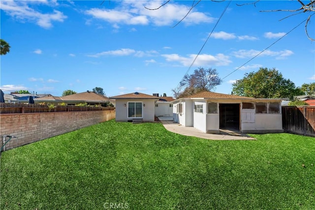 back of house with stucco siding, a lawn, and fence private yard