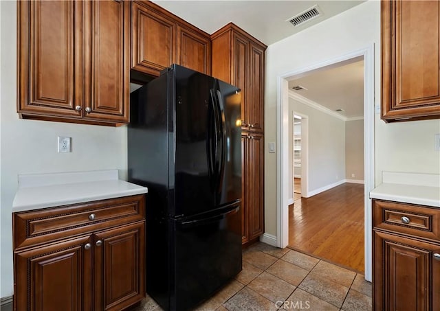 kitchen featuring visible vents, light countertops, crown molding, and freestanding refrigerator