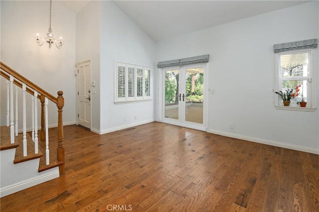 entryway with high vaulted ceiling, stairway, baseboards, and wood finished floors