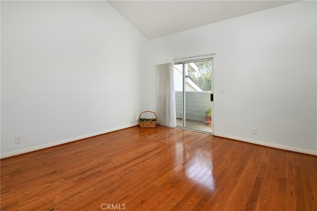 empty room with vaulted ceiling, wood finished floors, and baseboards