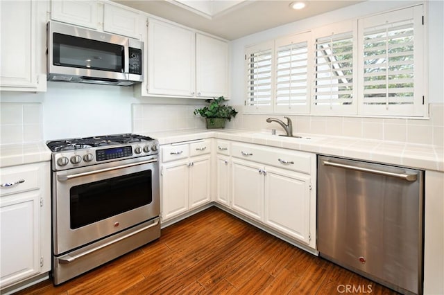 kitchen featuring white cabinetry, appliances with stainless steel finishes, tasteful backsplash, and tile counters