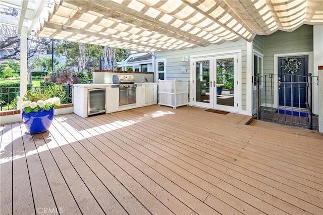 deck featuring french doors, an outdoor kitchen, a grill, and a pergola