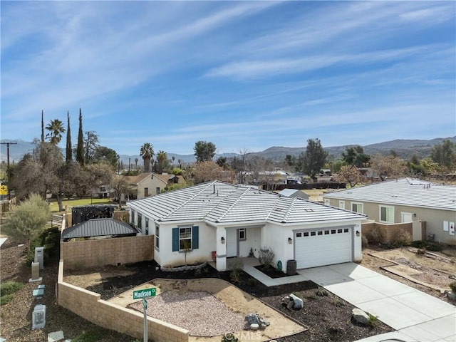 ranch-style home featuring driveway, an attached garage, fence, a mountain view, and stucco siding