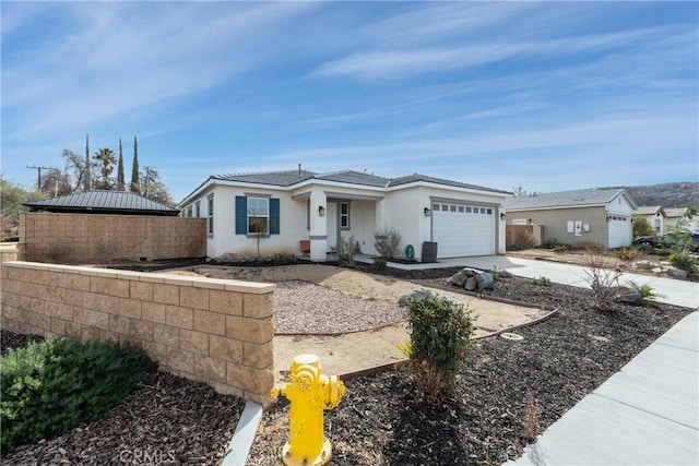 view of front of house featuring a garage, driveway, fence, and stucco siding