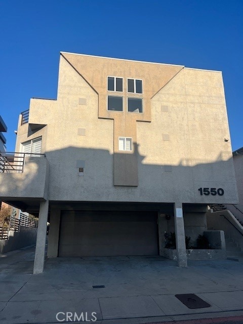 view of front of property featuring an attached garage, driveway, stairs, and stucco siding