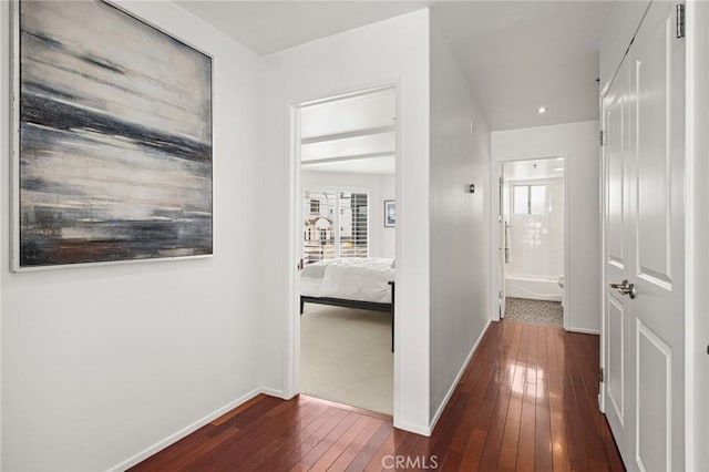 corridor with dark wood-type flooring and baseboards