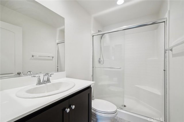 full bathroom featuring toilet, a shower stall, and vanity