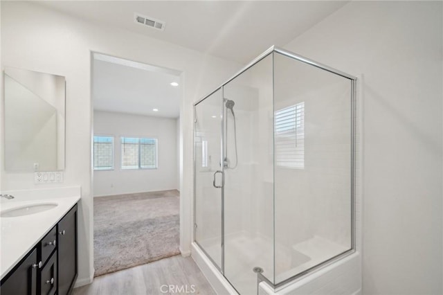 bathroom featuring a stall shower, visible vents, wood finished floors, and vanity