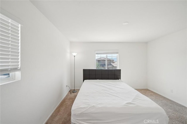 bedroom with light colored carpet and baseboards