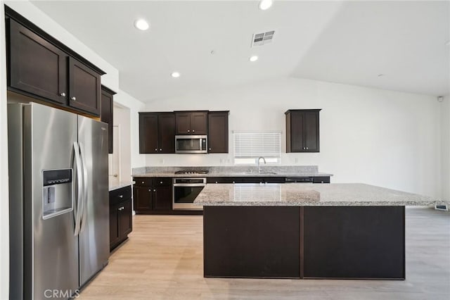 kitchen with visible vents, lofted ceiling, appliances with stainless steel finishes, a center island, and dark brown cabinets