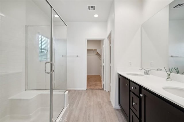 full bathroom with a stall shower, a walk in closet, visible vents, and a sink