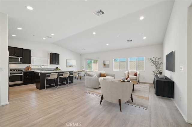 living area featuring lofted ceiling, visible vents, light wood-style flooring, and recessed lighting