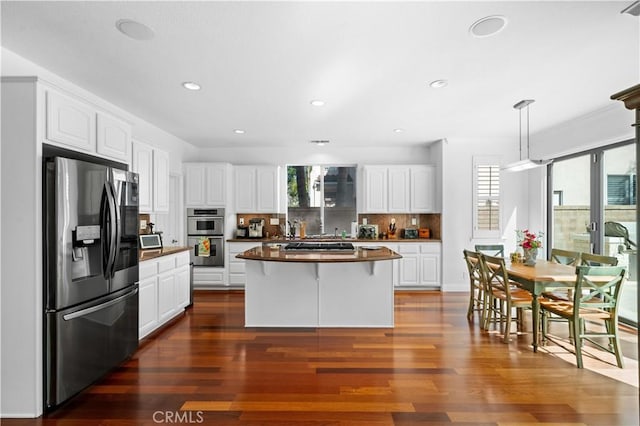 kitchen with pendant lighting, appliances with stainless steel finishes, white cabinetry, and a center island