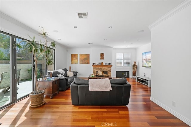 living area featuring crown molding, visible vents, a fireplace, and wood finished floors