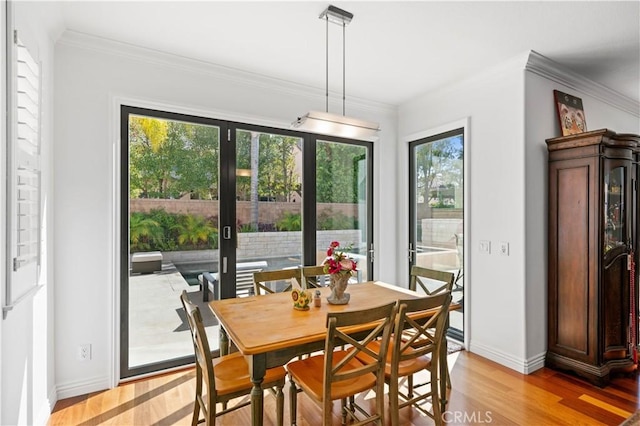 dining area with light wood-style flooring, baseboards, and crown molding