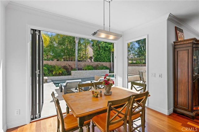 dining room with crown molding, baseboards, and light wood-style floors